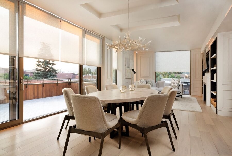 A dining room with J-Geiger motorized shades halfway down floor-to-ceiling windows.